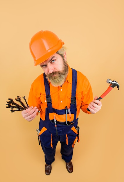 Serious worker holds repair tools repairment tools spanner hammer screwdriver building builder in