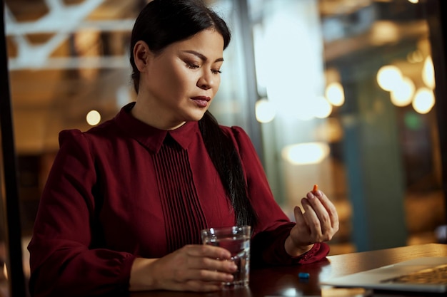 Serious young Asian woman looking at medicine