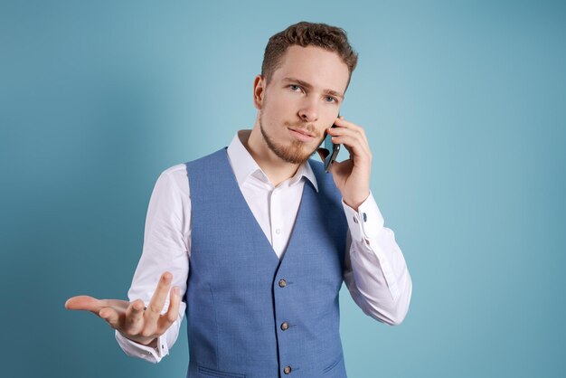 Serious young bearded business man in classic suit which is positioned on blue