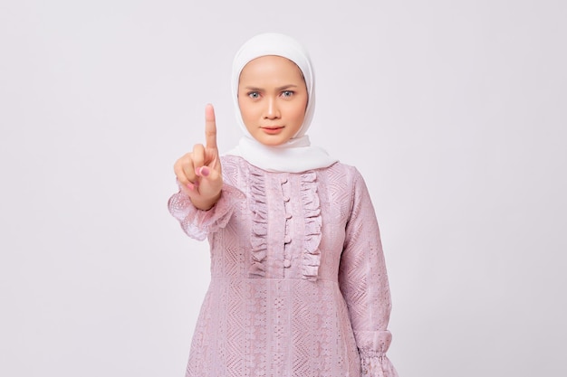 Serious young beautiful Asian Muslim woman 20s wearing hijab showing stop gesture at the camera with an angry expression isolated on white background People religious lifestyle concept