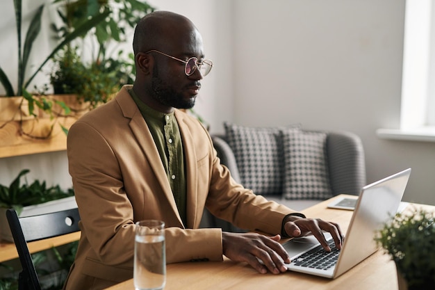 Serious young black man in formalwear consulting online patients in office