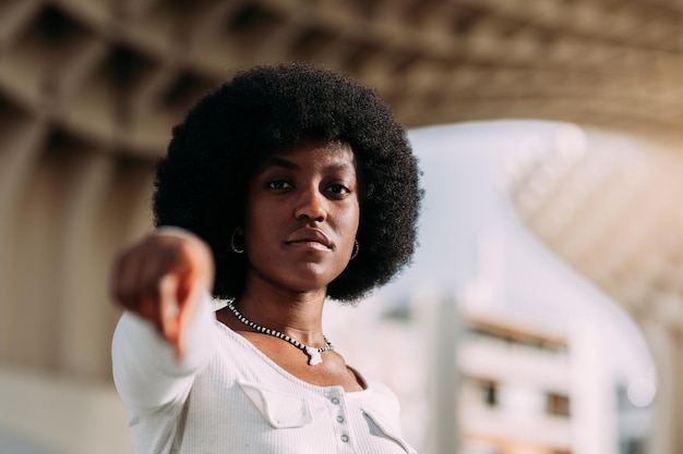 Serious young black woman with afro hair pointing finger Girl power concept Horizontal