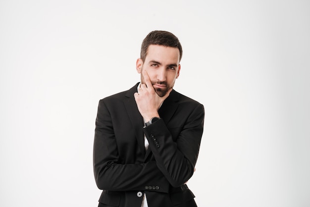 Serious young businessman posing over white wall