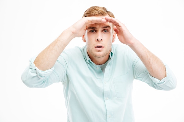 Serious young businessman standing and looking far away