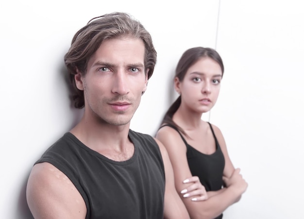 Serious young couple standing near the wall