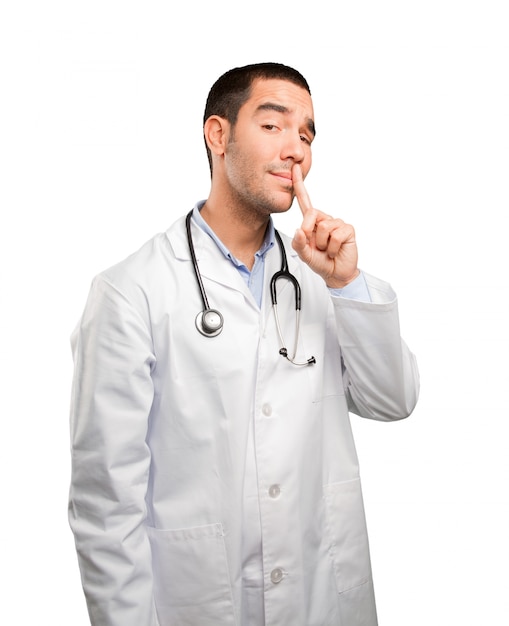 Serious young doctor doing a silence gesture