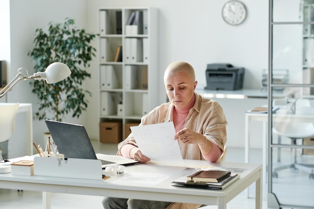 Serious young female analyst sitting at desk in office