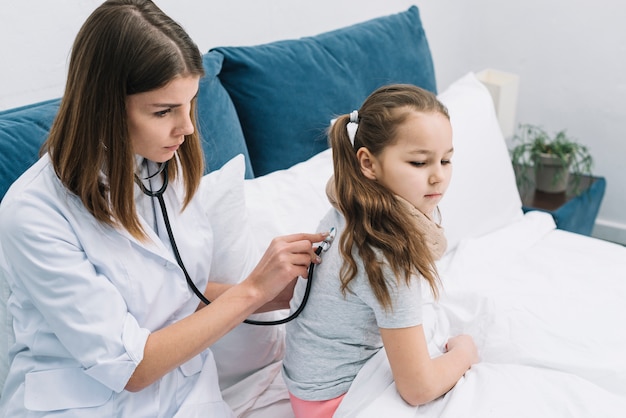 Foto giovane medico femminile serio che esamina la parte posteriore della ragazza