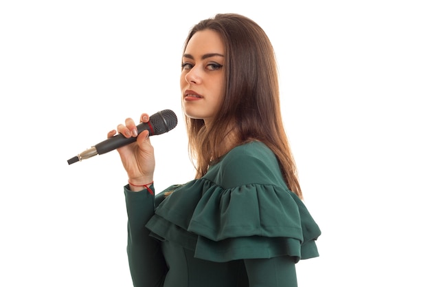 Серьезная молодая девушка поет караоке в микрофон, изолированные на белом фоне