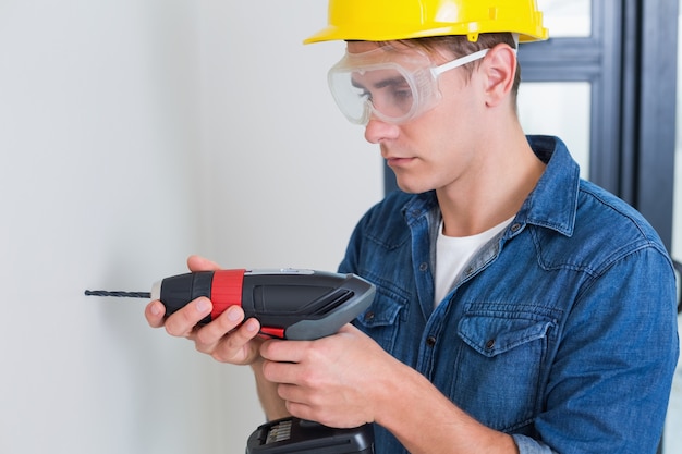 Serious young handyman using a drill