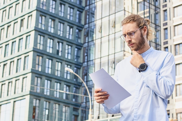 Serious young male businessman examines a documents