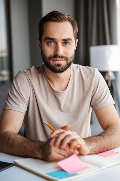 a serious young man indoors at home writing notes sit at the table