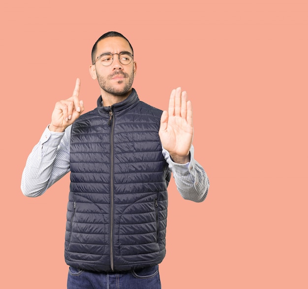 Serious young man making a gesture of stop with his palm