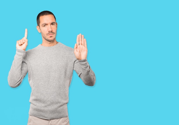 Serious young man making a gesture of stop with his palm