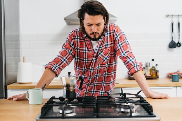 Foto giovane serio che prepara caffè in cucina