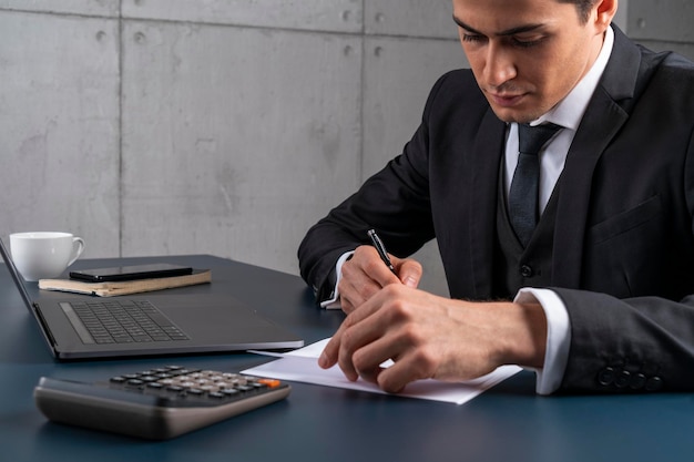 Serious young man signing document in office