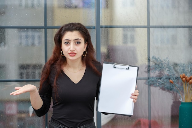 Serious young woman holding her notebook and looking at the camera