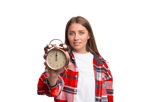 Serious young woman is showing an alarm clock to the camera.