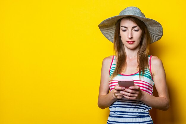 Serious young woman looking at the phone, wearing a hat and a striped dress