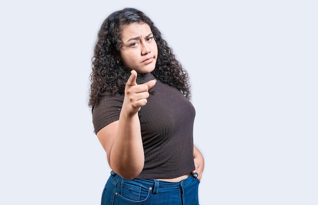 Photo serious young woman pointing at the camera isolated young girl pointing at you frowning isolated