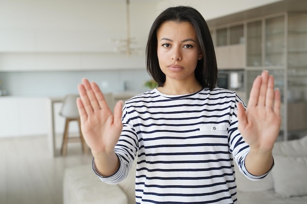 写真 真面目な若い女性が自宅で禁止不一致拒否の手のひらで停止ジェスチャーを表示