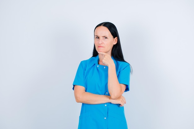 Seriously doctor is thinking by holding hand under chin on white background