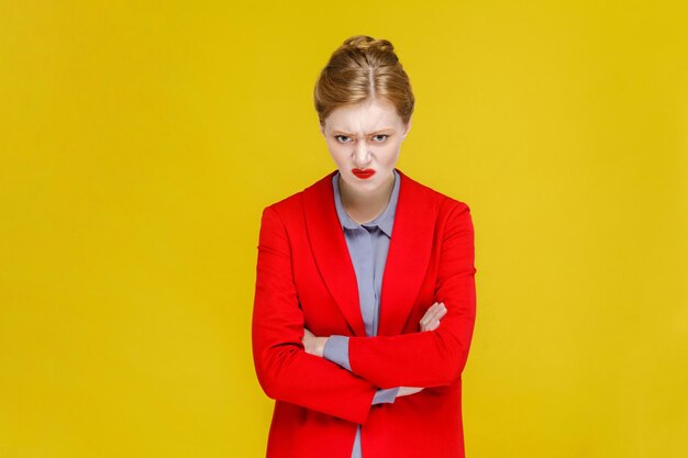 Seriously nervous boss in suit looking at camera. Studio shot, isolated on yellow background