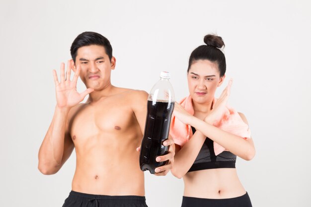 Seriously  young fitness  man and his girlfriend not drink a cola water. Fitness and healthy lifestyle concept. Studio shot on white background.