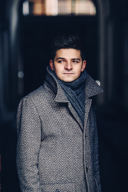 Seriously young man in warm coat on a dark street