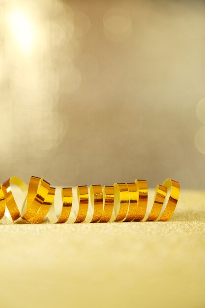 Serpentine ribbon on table on golden shiny background