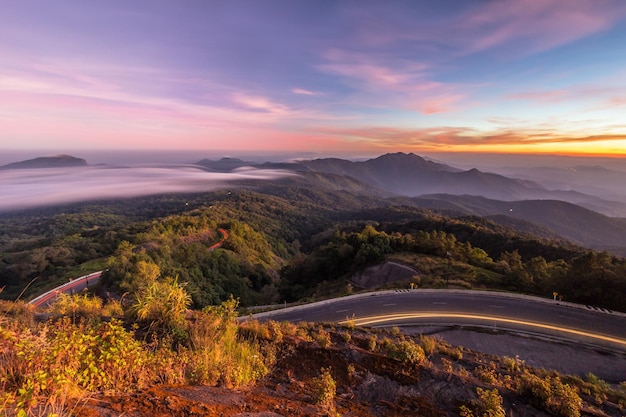 Serpentine weg bochten met verkeerspaden, bergen en lucht bij zonsondergang. Nationaal park Doi Inthanon, Thailand