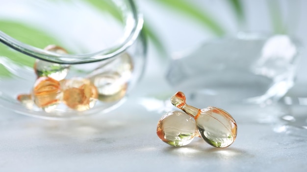 Serum capsules blurred background with ice glass jar with the capsules and green palm leaf