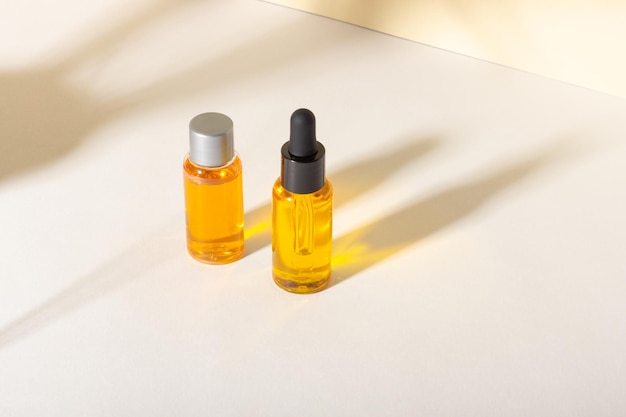 Serum and essential cosmetic oil bottle with dropper with shadows on the background Skincare beauty spa product and pipette