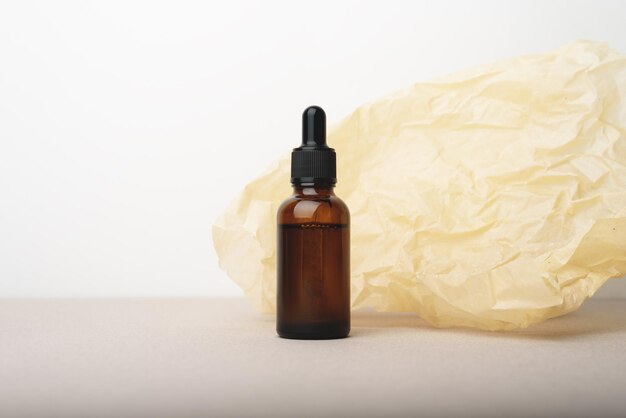 Serum glass bottle with pipette on beige wrinkle paper background