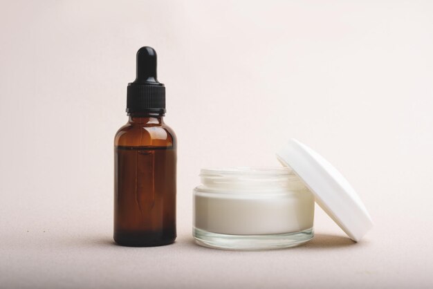 Serum glass bottle with pipette and jar of facial or body cream