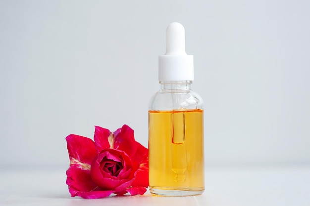 Serum in een cosmetische fles met een druppelaar en een roze bloem. Biologische SPA-cosmetica