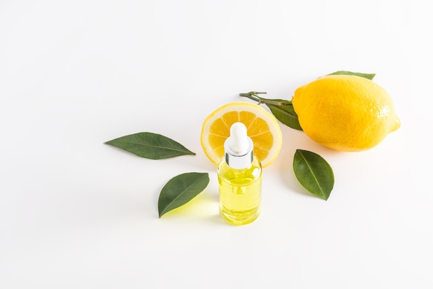 Serum met vitamine C tegen de achtergrond van een sappige citroen in een cosmetische fles met een pipet het concept van het bestrijden van pigmentatie en rimpels