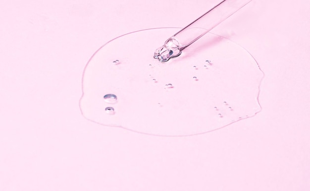 Serum smear stain sample with retinol collagen and peptides in\
a dropper on a pink background skin care liquid gel transparent\
sample drop with bubbles in a pipette cosmetology beauty\
concept