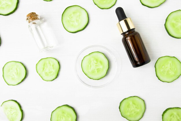 Serum and tonic in glass containers on a white background with cucumber slices top view