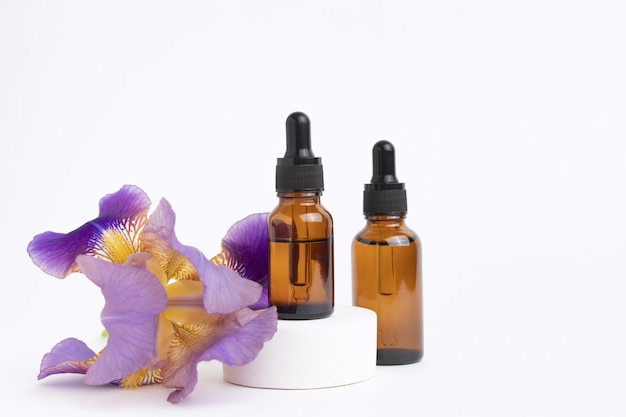 Serum with floral extracts for skincare Face and body care spa concept Nature cosmetics in glass bottle with a pipette and with iris flower on white background