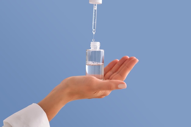 Serum with a pipette in female hands on a blue background