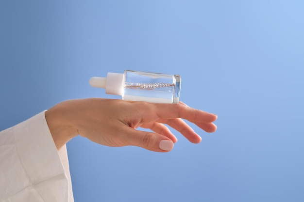 Photo serum with a pipette in female hands on a blue background