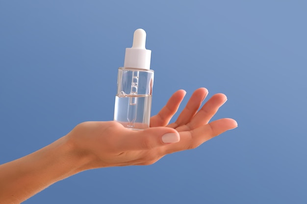 Serum with a pipette in female hands on a blue background