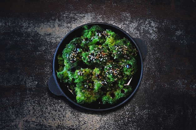 Photo serve baked broccoli with sauces and sesame seeds.