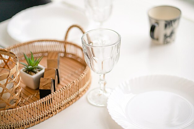 Served and decorated white table with glasses plates and a mug\
table decoration with wicker and wooden decor elements