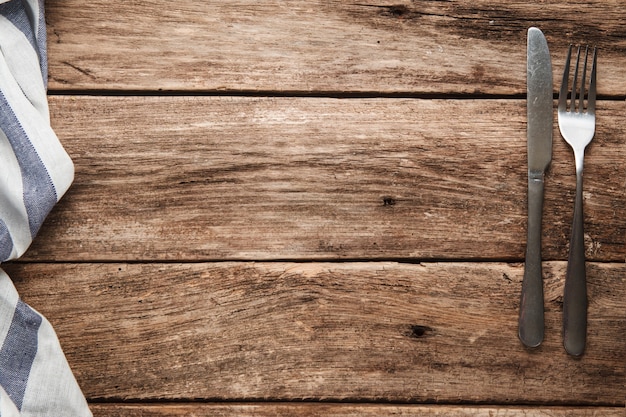 Served rustic wooden table with fork, knife and napkin. surface