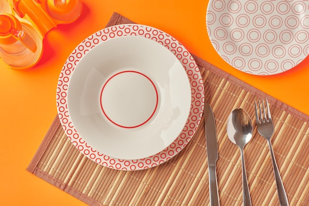 Served table for food with plates forks spoon on orange background