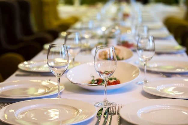 Served table in a restaurant Plates glasses cutlery on a long table