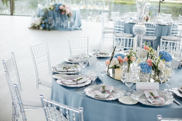 Served wedding table with decorative fresh pink blue flowers and candles Celebration details