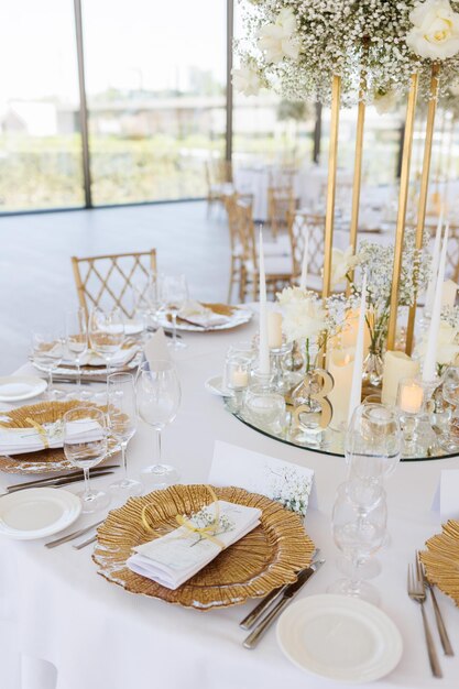 Served wedding tables with golden plates decorative fresh flowers and candles